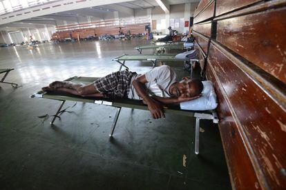 Un home dorm sobre un llit plegable a la National Arena, el principal refugi de Kingston (Jamaica).