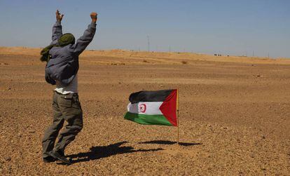 Un miembro del Frente Polisario se manifiesta ante los soldados marroqu&iacute;es, al fondo de la imagen,  apostados en el muro constru&iacute;do por Marruecos.