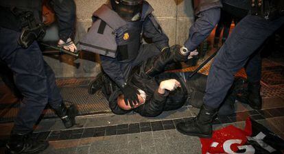 Varios polic&iacute;as arrestan a un manifestante.