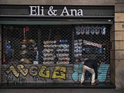 Una persona echa el cierre a un comercio en Barcelona.