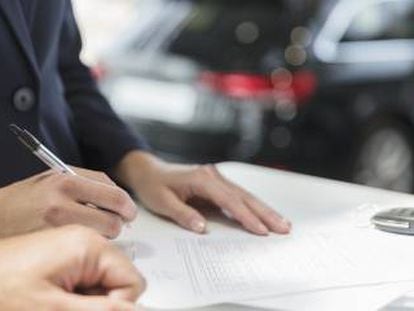 Un cliente firma un contrato financiero en un concesionario de coches.  