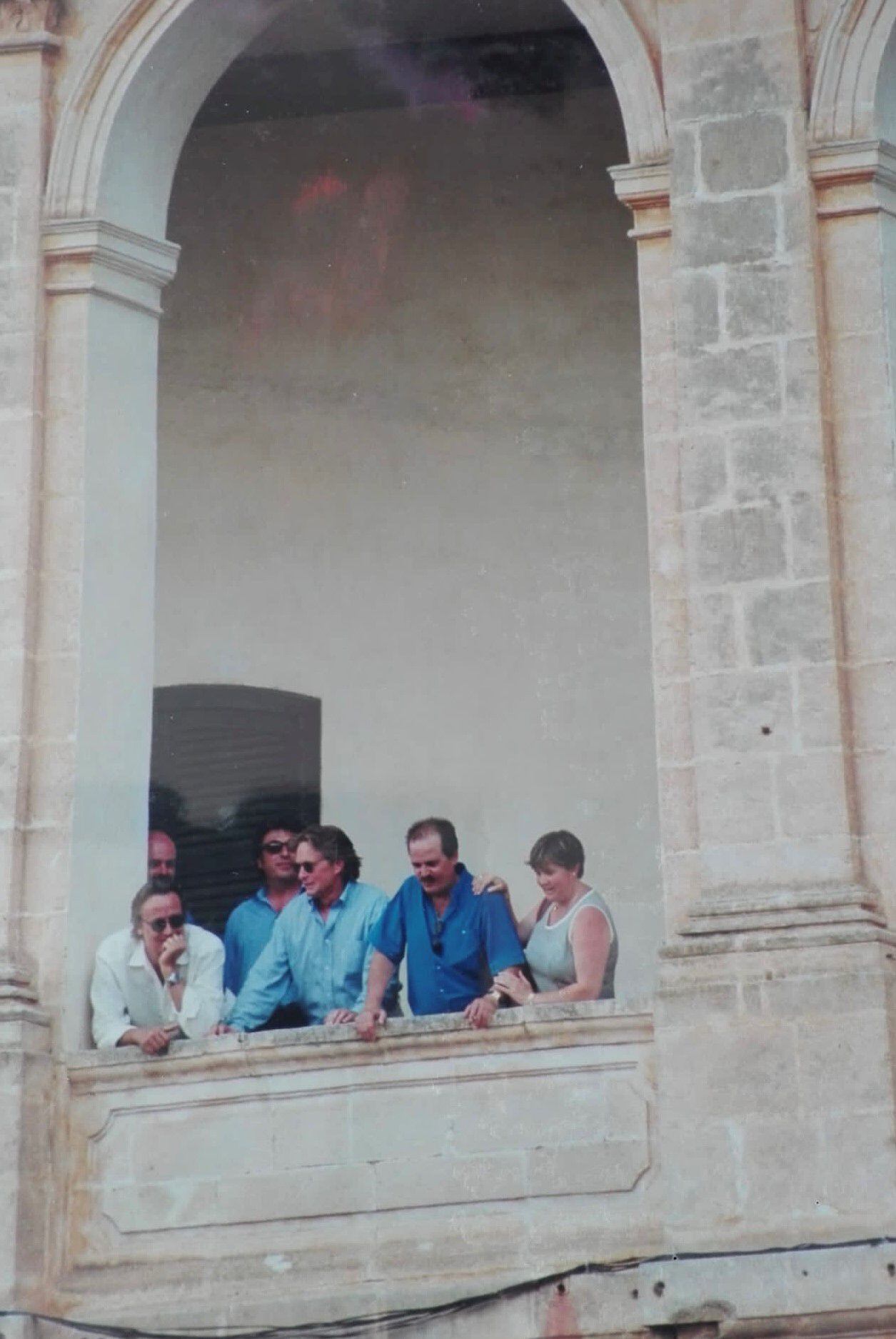 Michael Douglas, el abogado Pep Gelabert y su hermana Nina, asomados al balcón para disfrutar de las fiestas de San Juan en la plaza de la Catedral de Ciutadella (Menorca).