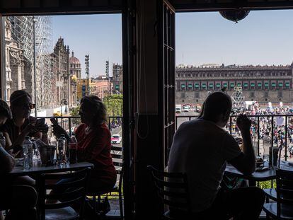 Turistas sentados en la terraza de un restaurante frente a la explanada del Zócalo de la Ciudad de México.