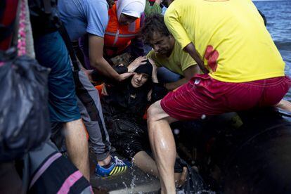 Voluntarios griegos y refugiados sirios ayudan a una mujer que acaba de llegar en un bote inflafle desde Turquía a la costa de la isla griega de Lesbos.