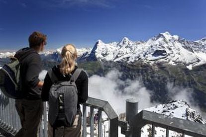 Dos turistas contemplando las cimas del Eiger, Monch y Jungfrau desde el mirador de Schilthorn, en los Alpes suizos.