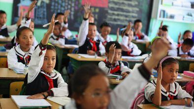 Los estudiantes de una clase de lengua tibetana levantan la mano para responder una pregunta en el colegio experimental de educación primaria de Lhasa, capital de la región autónoma de Tíbet, en junio de 2009.