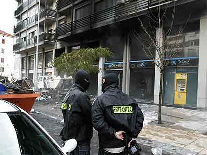 Dos <i>ertzainas</i> vigilan el edificio atacado en Mondragón.