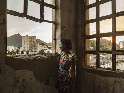 Mulher em frente às janelas do edifício abandonado do Ministério da Fazenda na favela da Mangueira, situada na zona norte do Rio de Janeiro, a menos de um quilômetro do estádio do Maracanã, epicentro da Copa do Mundo de futebol e dos Jogos Olímpicos do Rio de Janeiro.
