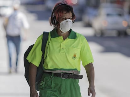 Una trabajadora de la limpieza camina protegida con mascarillas.