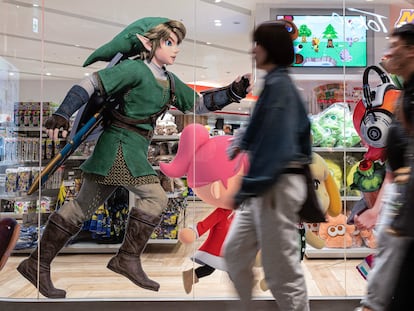 Viandantes caminan frente a un escaparate en Tokio que muestras publicidad del último 'Zelda'.