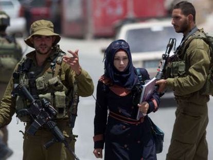 Una mujer palestina pasa junto a soldados israel&iacute;es en Hebr&oacute;n. 