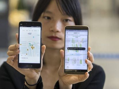 Una mujer china muestra las aplicaciones de Didi y de Uber en China