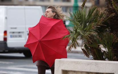 Una mujer se protege del viento en San Sebastián.