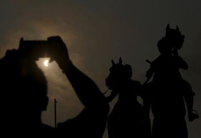 Un home utilitza el seu telèfon mòbil per fotografiar l'eclipsi solar a Penh (Cambodja).