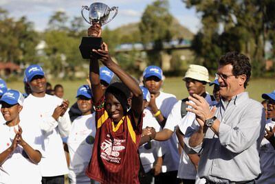 Fabio Capello aplaude a un niño que levanta un trofeo en Lesoto.