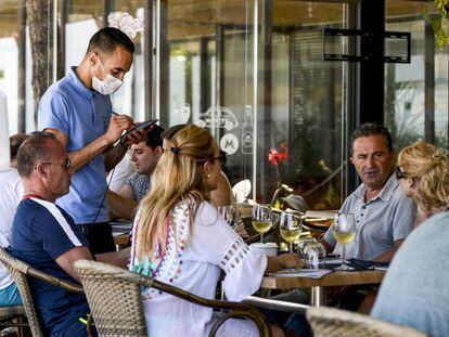 Un camarero toma nota a unos comensales en la terraza de un restaurante del Paseo Maritimo de Playa de Aro, Costa Brava (Girona).