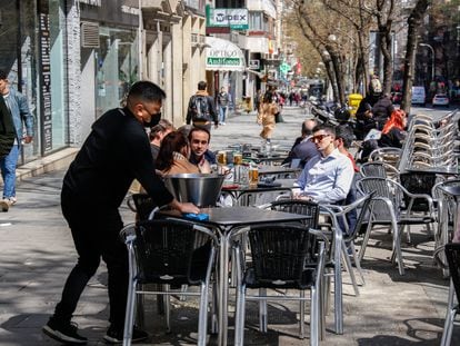 Un camarero limpia una mesa en una terraza en la plaza Manuel Becerra de Madrid, el pasado mayo.