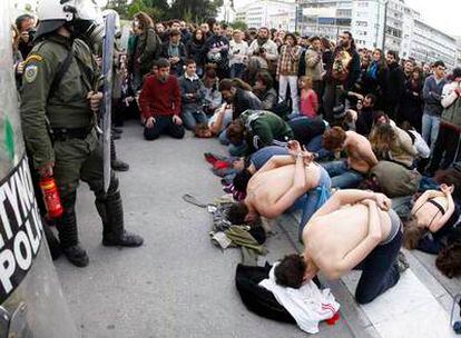 Varios manifestantes simulan ser prisioneros ante los policías antidisturbios que vigilan la sede del Parlamento en Atenas.