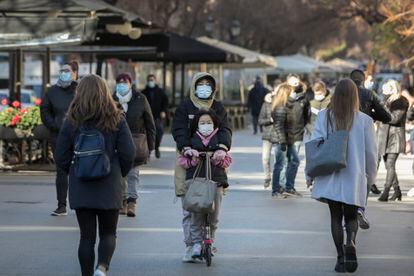 Una mujer conduce un patinete por una zona peatonal de Barcelona y llevando a una niña, dos cuestiones prohibidas con la nueva norma de circulación.