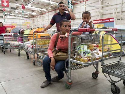 Una familia hace fila para comprar v&iacute;veres en un supermercado en Caracas.