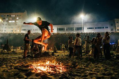 Un joven salta una hoguera en la playa de Riazor, durante la celebración de la Noche de San Juan. 