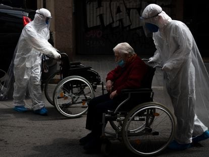 Un voluntario de la ONG Open Arms traslada a un anciano en silla de ruedas a un hospital de Barcelona.