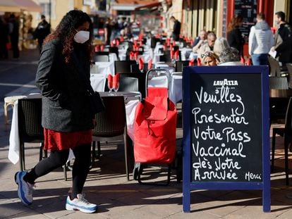 Un mujer pasa junto a un cartel en una terraza de Niza (Francia) con el siguiente mensaje: "Por favor, presente su pase vacunal cuando llegue".