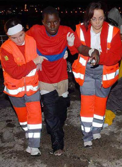 Dos miembros de la Cruz Roja ayuda a uno de los 36 inmigrantes que llegaron en un cayuco, al puerto de Arguinegüin, al sur de Gran Canaria.