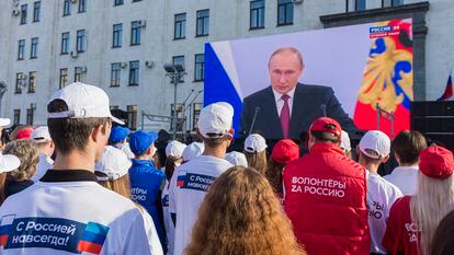 Un grupo de personas sigue un discurso del presidente ruso, Vladímir Putin, en Lugansk (Ucrania).