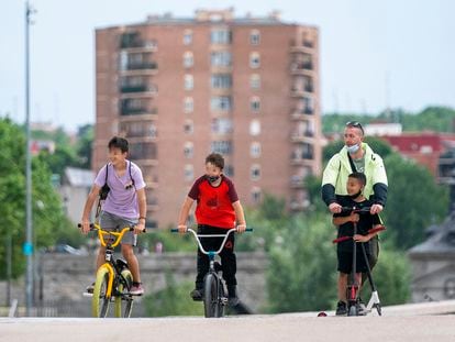 Dos niños en bici y un hombre con otro menor en patinete pasean por Madrid Río en la capital este sábado.