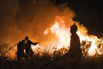 Tres integrantes de la brigada municipal de Maceda intentan sofocan un incendio en el municipio.