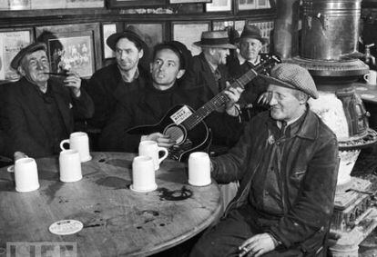 Woody Guthrie actuando en una taberna de Nueva York en 1943 con su famosa guitarra con el lema impreso 'Esta máquina mata fascistas'.