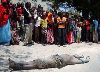 Un grupo de somalíes miran el cadáver de un militante islamista tras haber sido arrastrado por las calles de Mogadiscio.