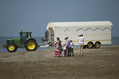 Un grupo de romeros mira uno de los tractores con una gran carroza desembarcada.