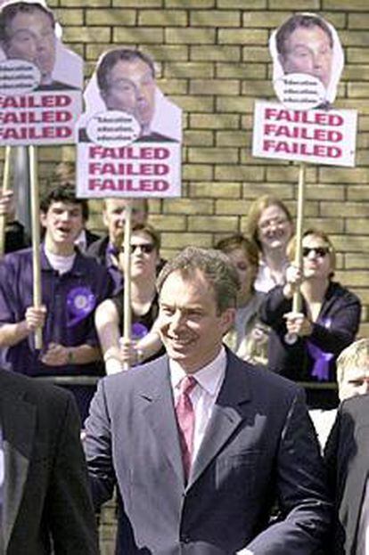 Tony Blair pasa ante un grupo de simpatizantes del Partido Conservador con carteles críticos con su gestión.
