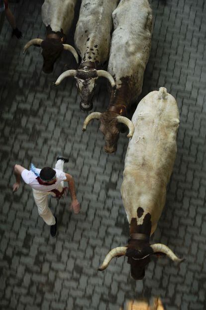 Un participante corre al lado de los toros durante la tercera jornada de la feria de San Fermín, en Pamplona.