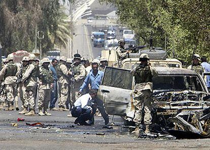 Soldados de EE UU y policías iraquíes revisan el coche destruido por una explosión a la entrada del cuartel general de las fuerzas ocupantes.