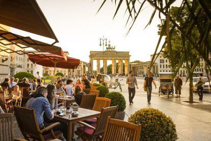 Una cafetería en Unter den Linden con la Puerta de Brandenburg al fondo.