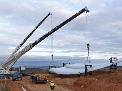 Las grúas levantan la pala de una turbina eólica cerca del pequeño pueblo soriano de Beltejar.