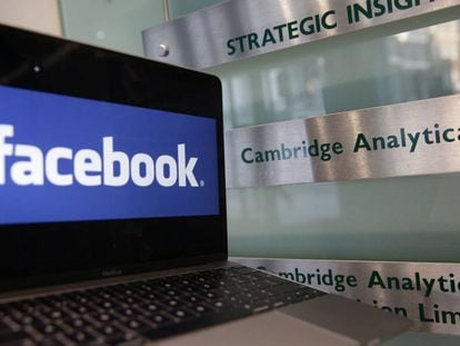 Un ordenador con el logo de Facebook junto a un cartel con el logo de Cambridge Analytica.