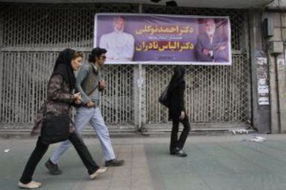 Transeúntes ante un cartel electoral este miércoles en Teherán.