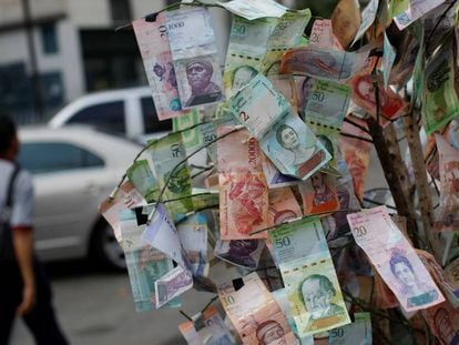 Un hombre pasa frente a billetes de bolívar tendidos en una calle de Caracas.