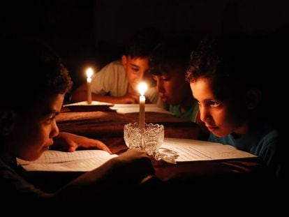 Ni&ntilde;os palestinos estudian en Gaza a la luz de las velas a causa de los apagones.