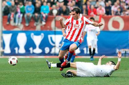 El atlético Godín salta sobre el sevillista Negredo.