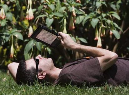 Un usuario de un libro electrónico disfruta de la lectura en un parque de Barcelona.