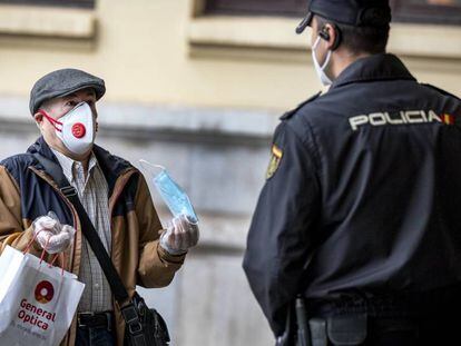 Un hombre muestra una mascarilla a un policía en la estación de Renfe de Valencia.