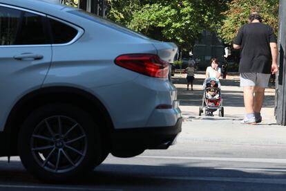 Una mujer pasa ante un SUV con su carrito de bebé, en Madrid.