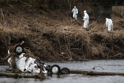 Agentes de policía de Fukushima, con trajes de protección contra la radiación, buscan víctimas del terremoto y tsunami en Minamisoma, dentro de la zona de exclusión.