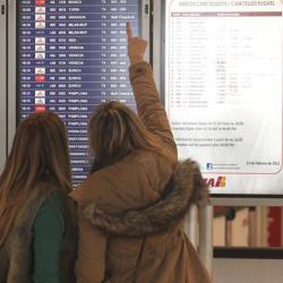 Pasajeros miran una pantalla en la T4 de Madrid-Barajas.