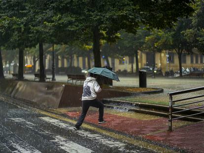 Un peatón cruza una calle entre una fuerte tromba de agua en Pamplona, el sábado.